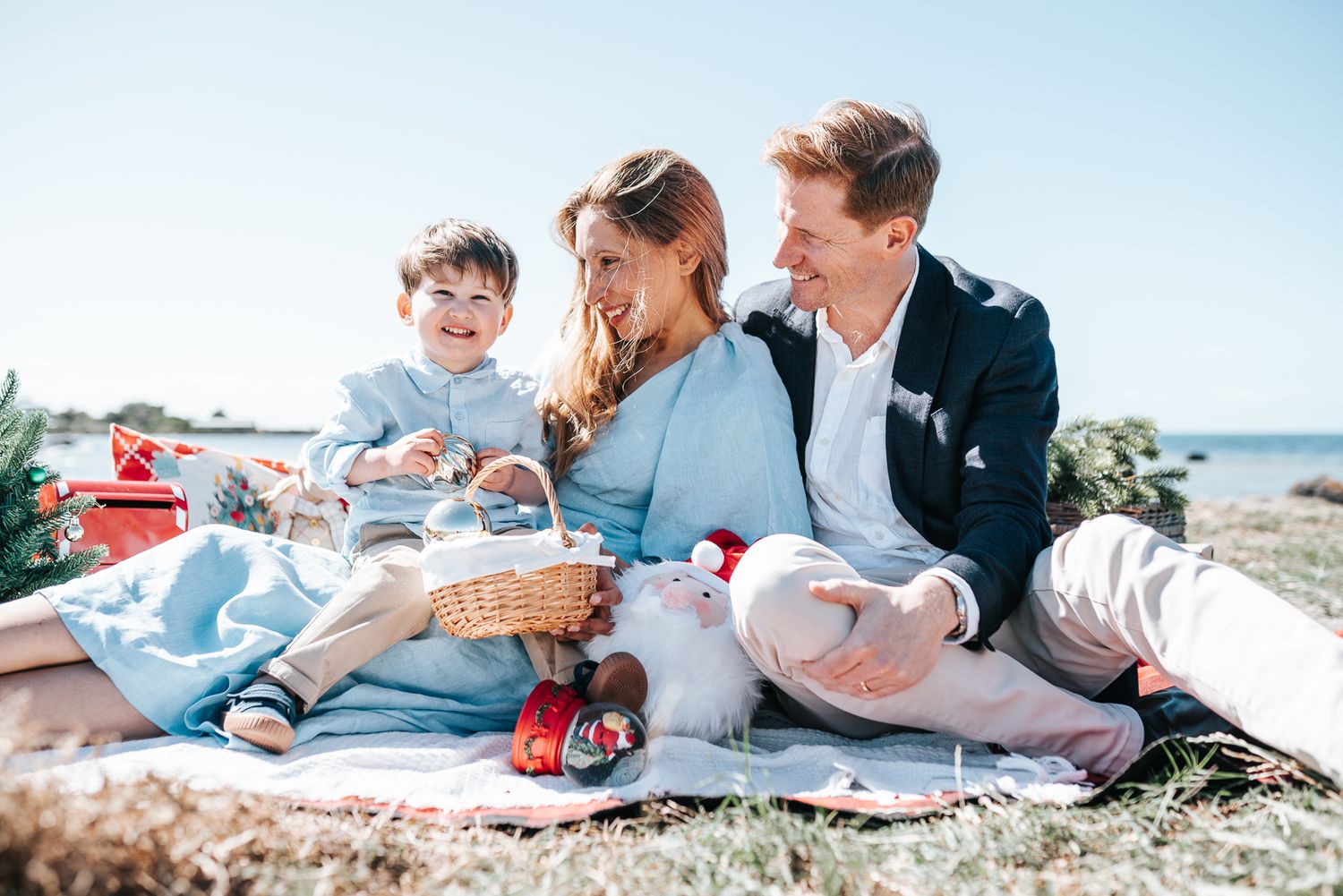 Happy family enjoying a sunny beach picnic with a wicker basket taken during a Melbourne Christmas Mini Session in the western suburbs.