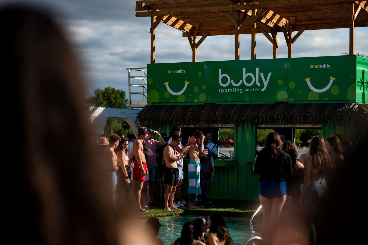 Crowd gathered around a Bubly sparkling water branded green booth at an outdoor summer festival event.