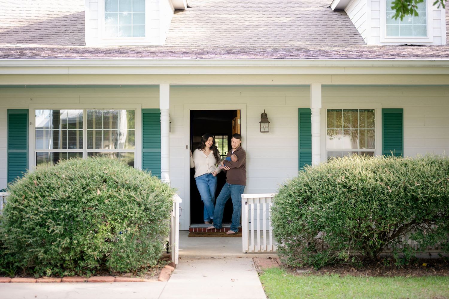 Lifestyle newborn family portraits in the doorway of a ranch-style home in Willis TX
