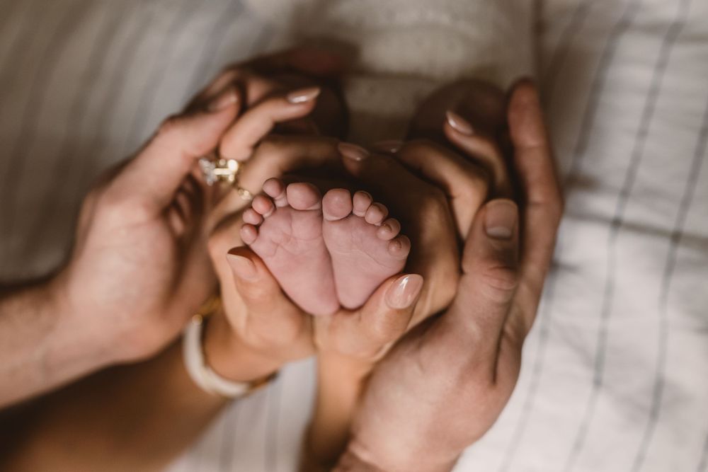 Parents tenderly cradling their newborn baby's tiny feet in their hands, a touching family moment.