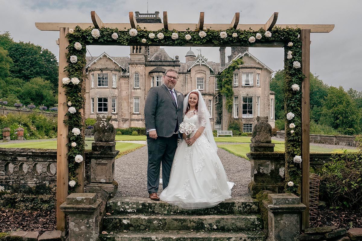Newlyweds beneath the garden arch during their Auchen Castle wedding