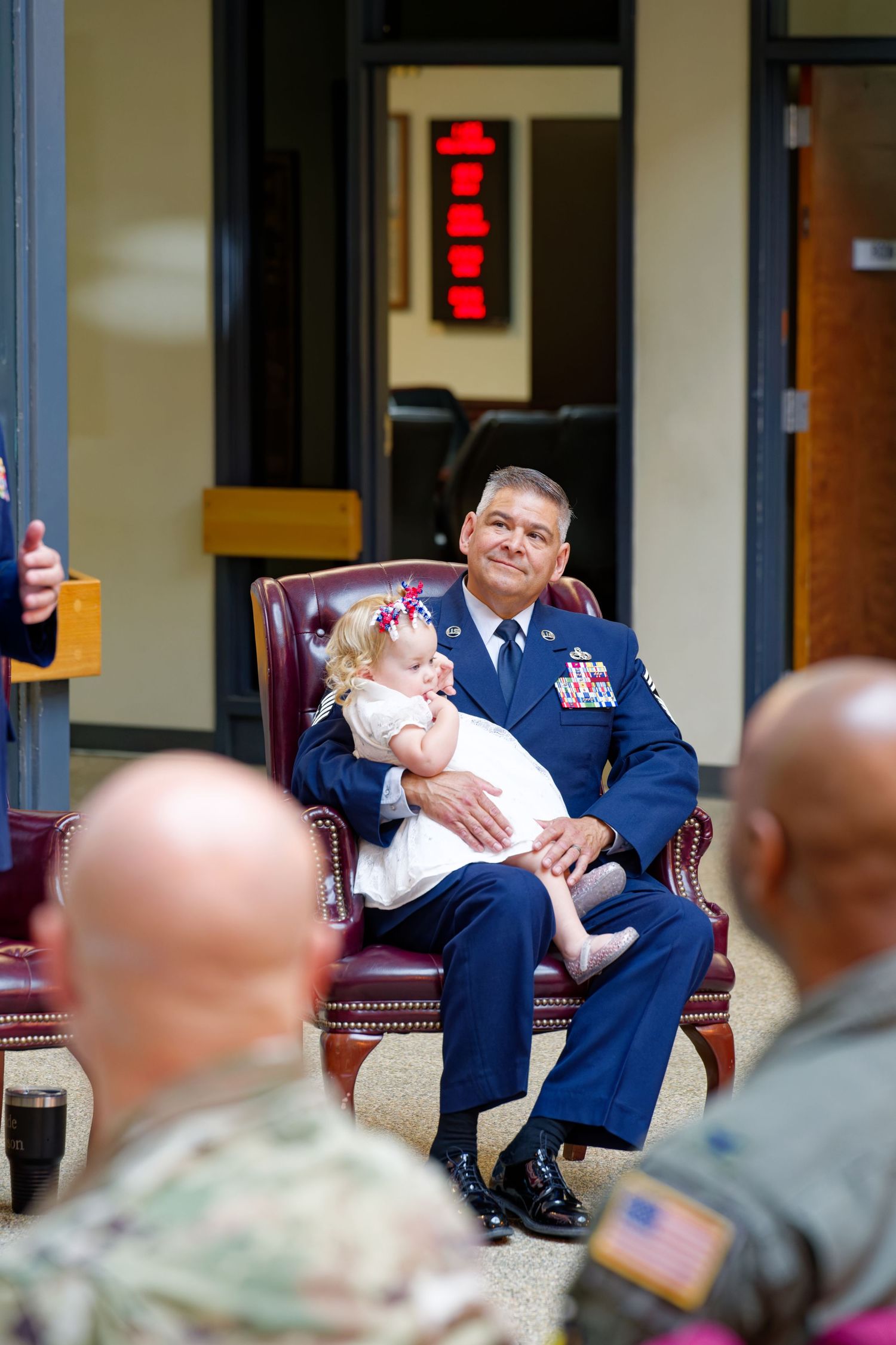 Air Force Chief Master Sergeant holds a baby girl during his military retirement ceremony.