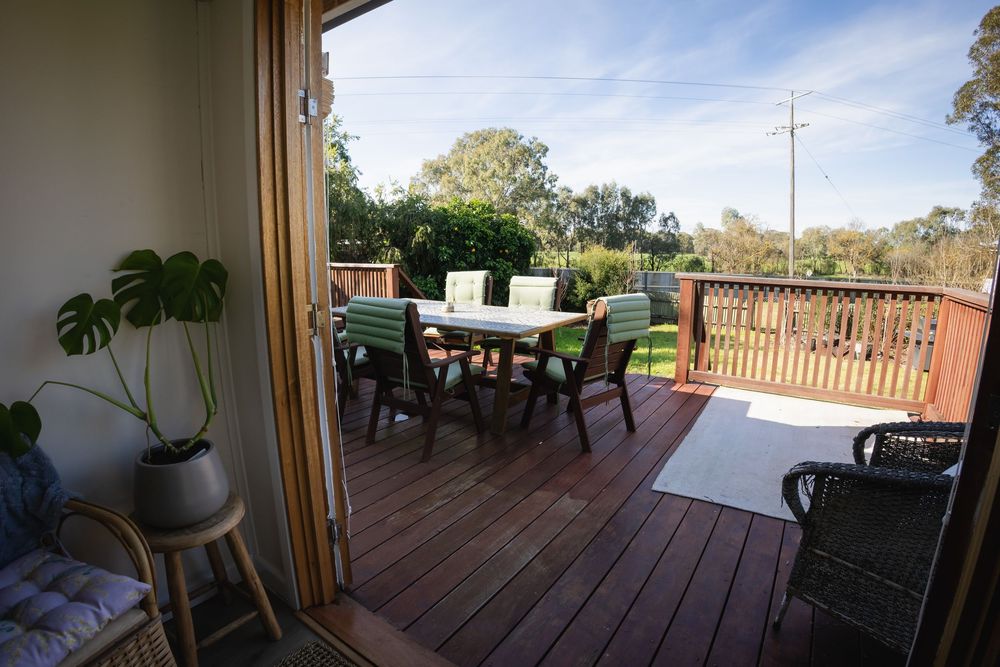 Spacious timber deck with outdoor dining set and lush garden views, perfect for alfresco entertaining.