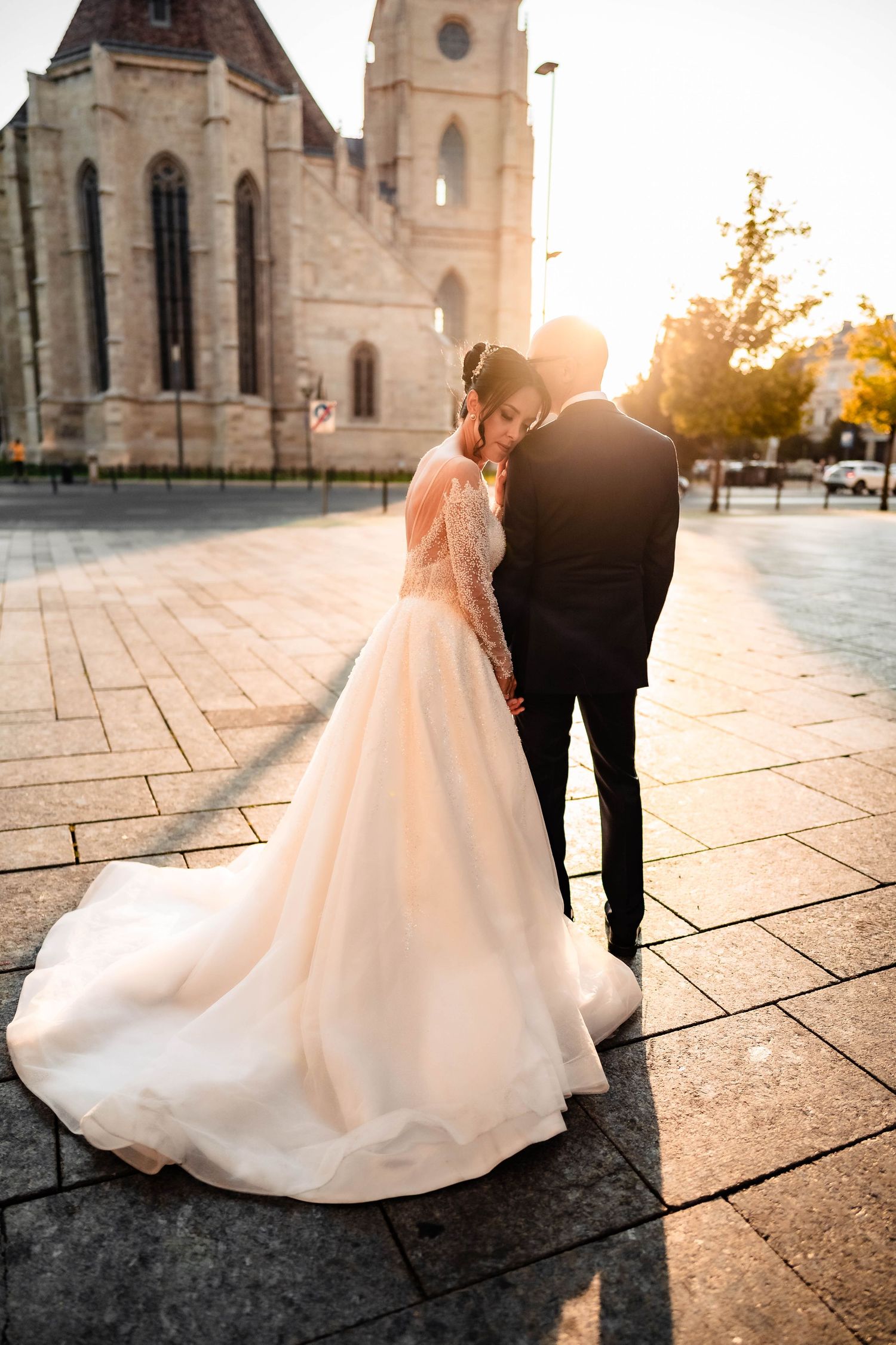 A bride and groom share a romantic moment together in an outdoor garden setting with lush greenery.