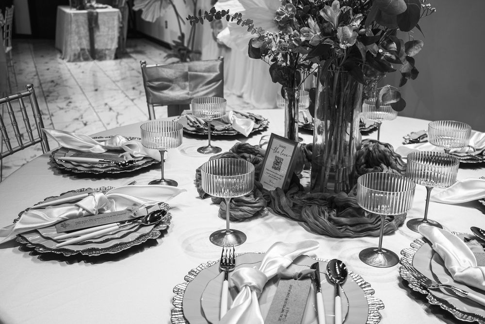Elegant black and white wedding table setting with floral centerpiece, charger plates, crystal glasses, and silverware.