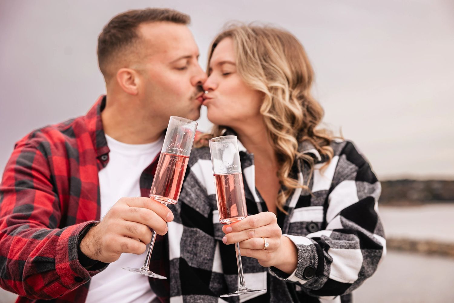 Two people toasting with champagne flutes filled with rosé, seated together in casual celebration. Engagement at Rockport MA