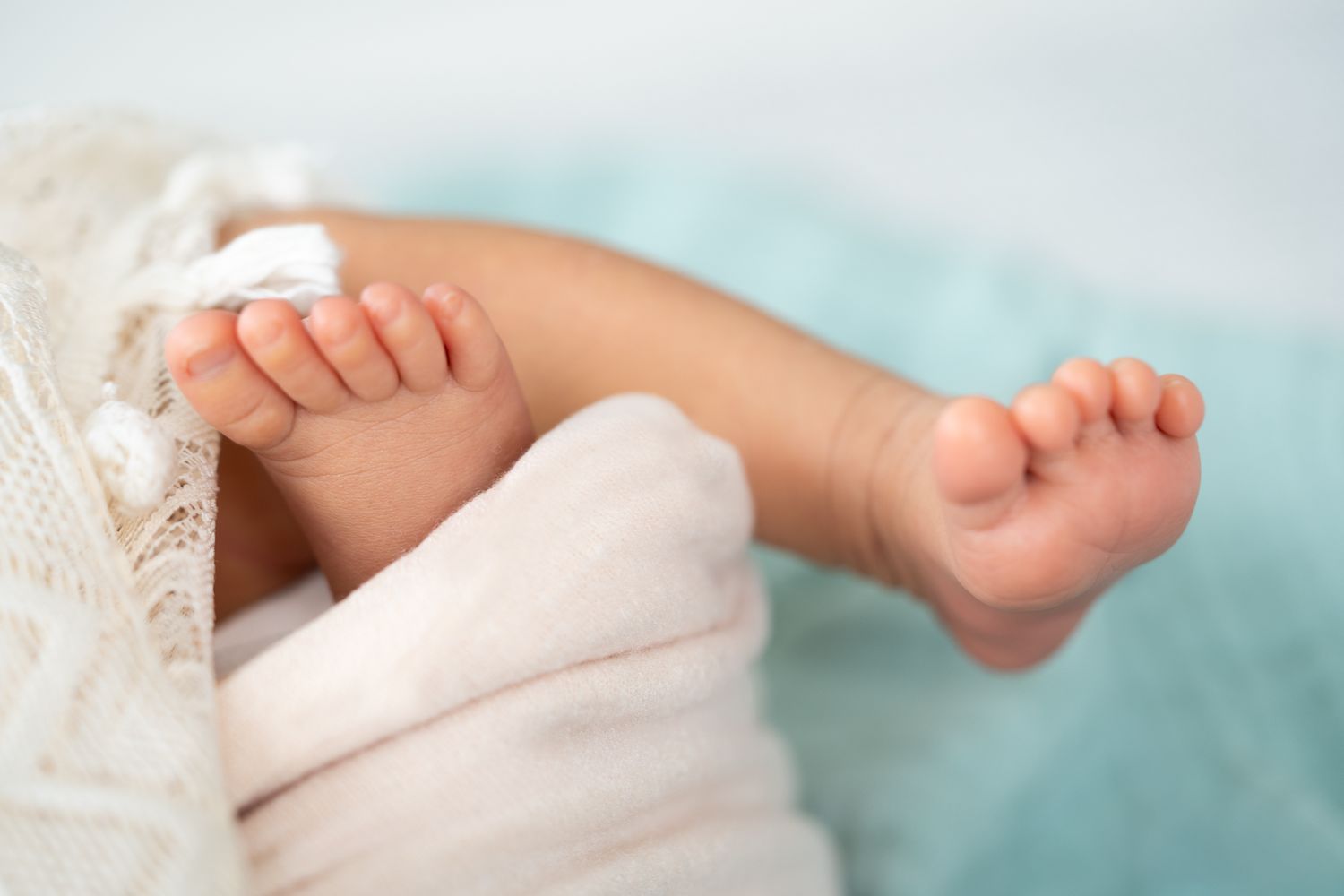 Tiny newborn feet resting against a soft blue blanket.
