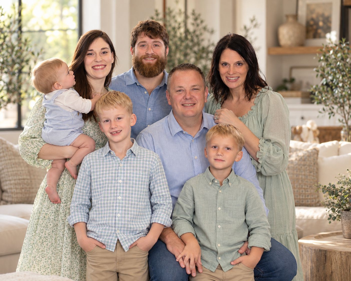 Happy family of six posing together in a bright, modern living room for a professional portrait photo.