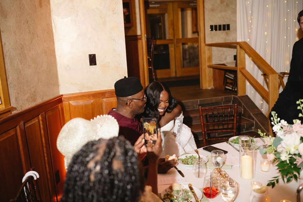 Couple sharing a joyful moment at a wedding reception dinner table with floral centerpieces and candlelight.