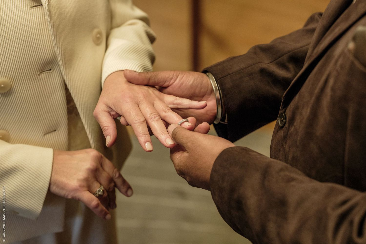 Close-up of a couple exchanging rings during a wedding ceremony, with one person placing a ring on the other's finger.