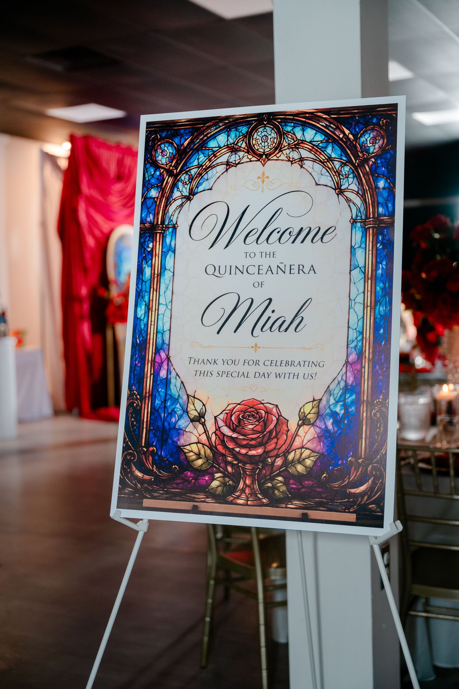 Stained glass style welcome sign for Miah's quinceañera with a red rose, displayed on an easel at a festive party venue.