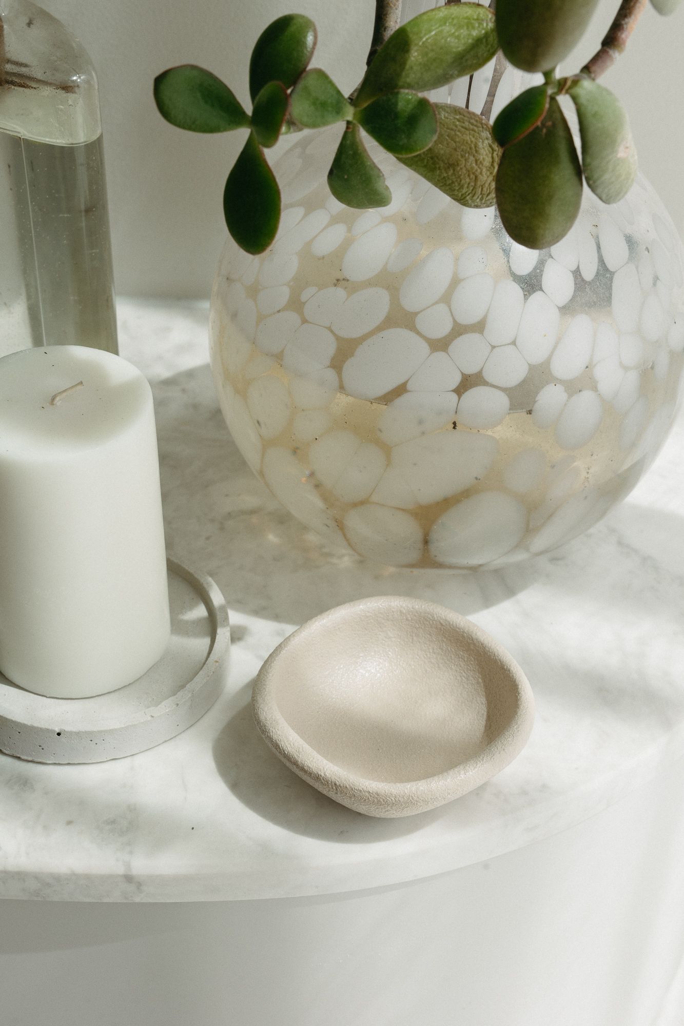 Marble shelf with white pillar candle, mosaic patterned vase with succulent, and small beige ceramic dish.