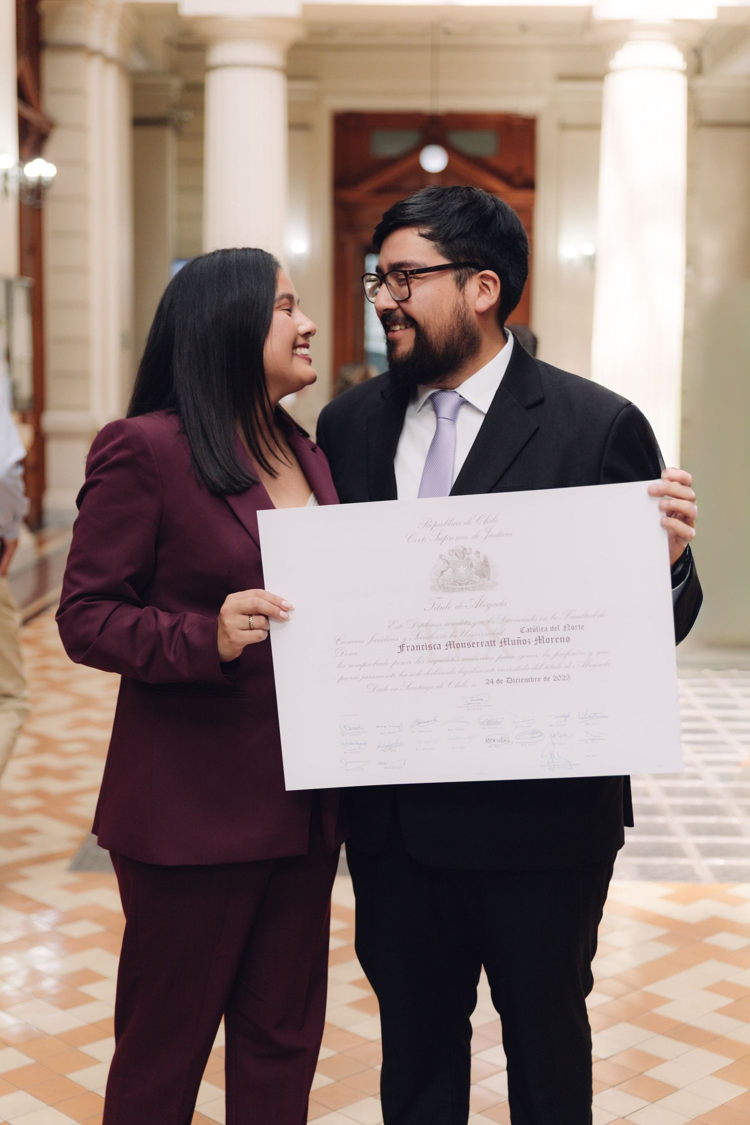 Man and woman in formal attire sharing a joyful moment with diploma.