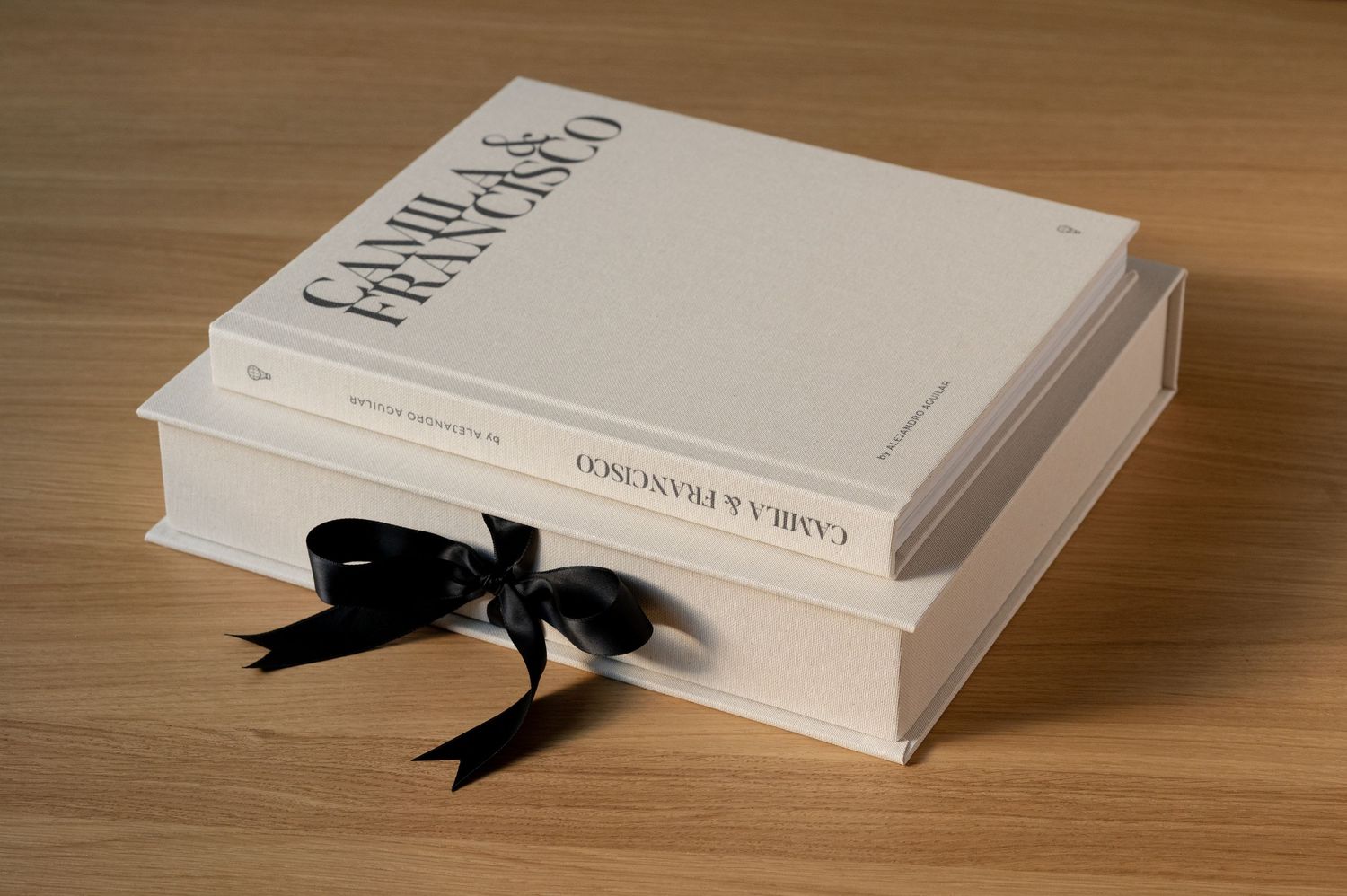Elegant white wedding photo album box with black ribbon bow engraved with couple names.