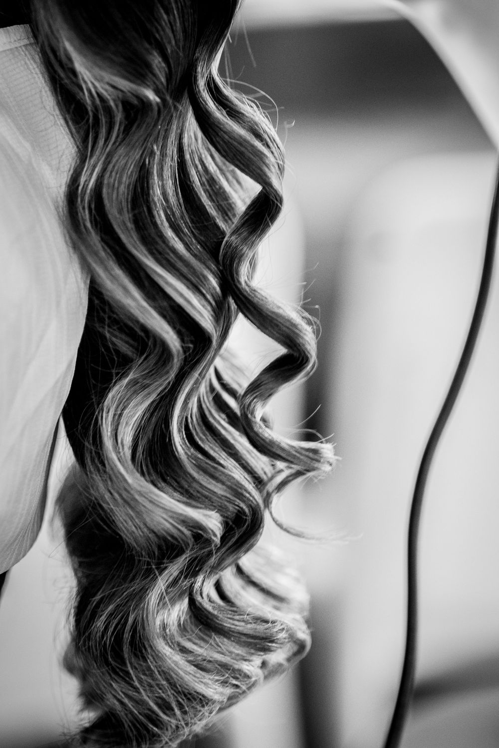 Black and white close-up of elegant curly hair with highlights, styled in loose waves for a bridal look.