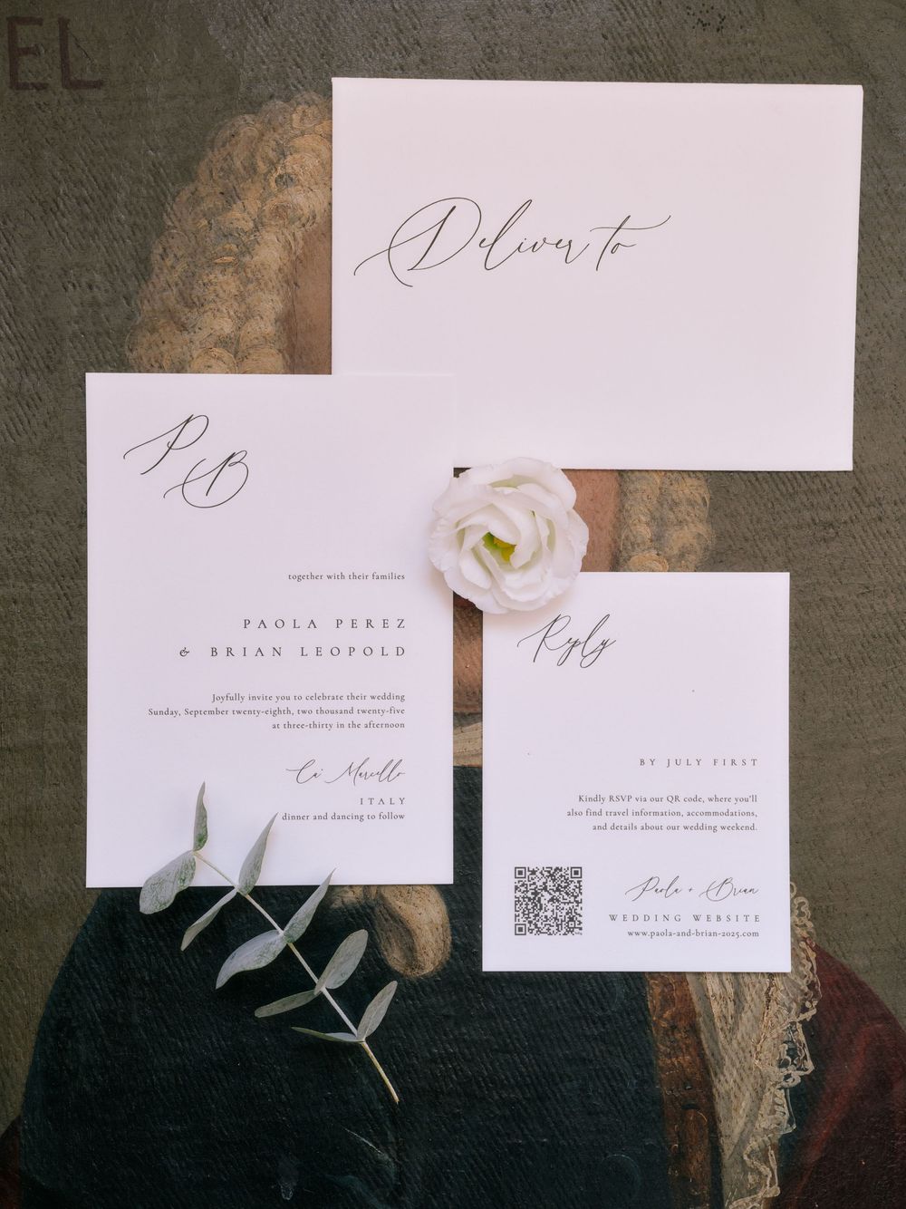 Elegant wedding invitation suite with white orchid flowers and minimalist typography on dark textured background.