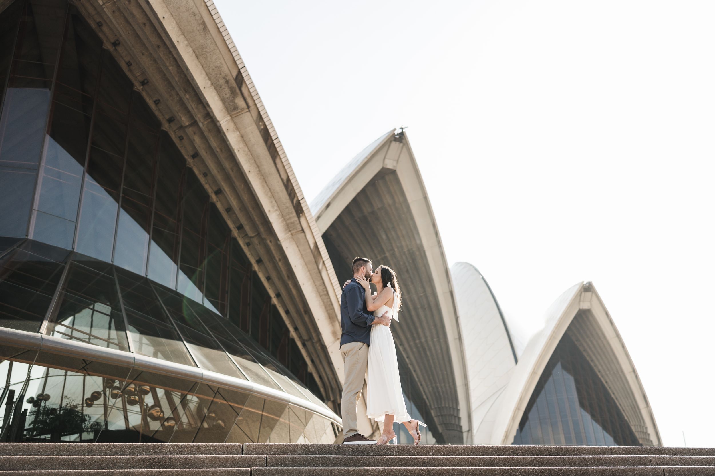 Couple embracing on the steps of the Sydney Opera House during an outdoor engagement photo session.
