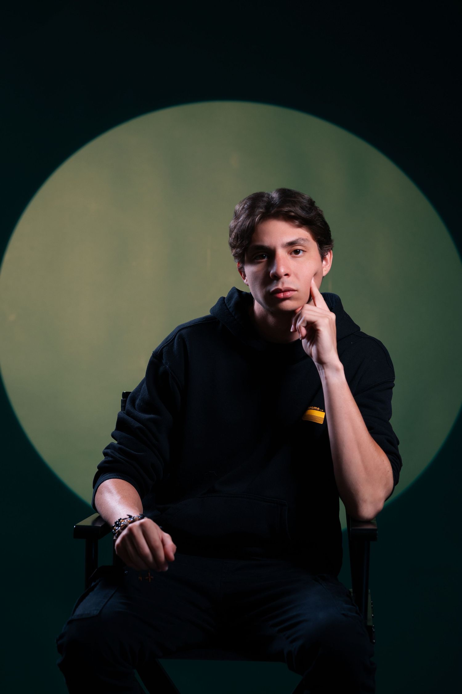 Creative portrait of a photographer holding a camera against a green studio backdrop