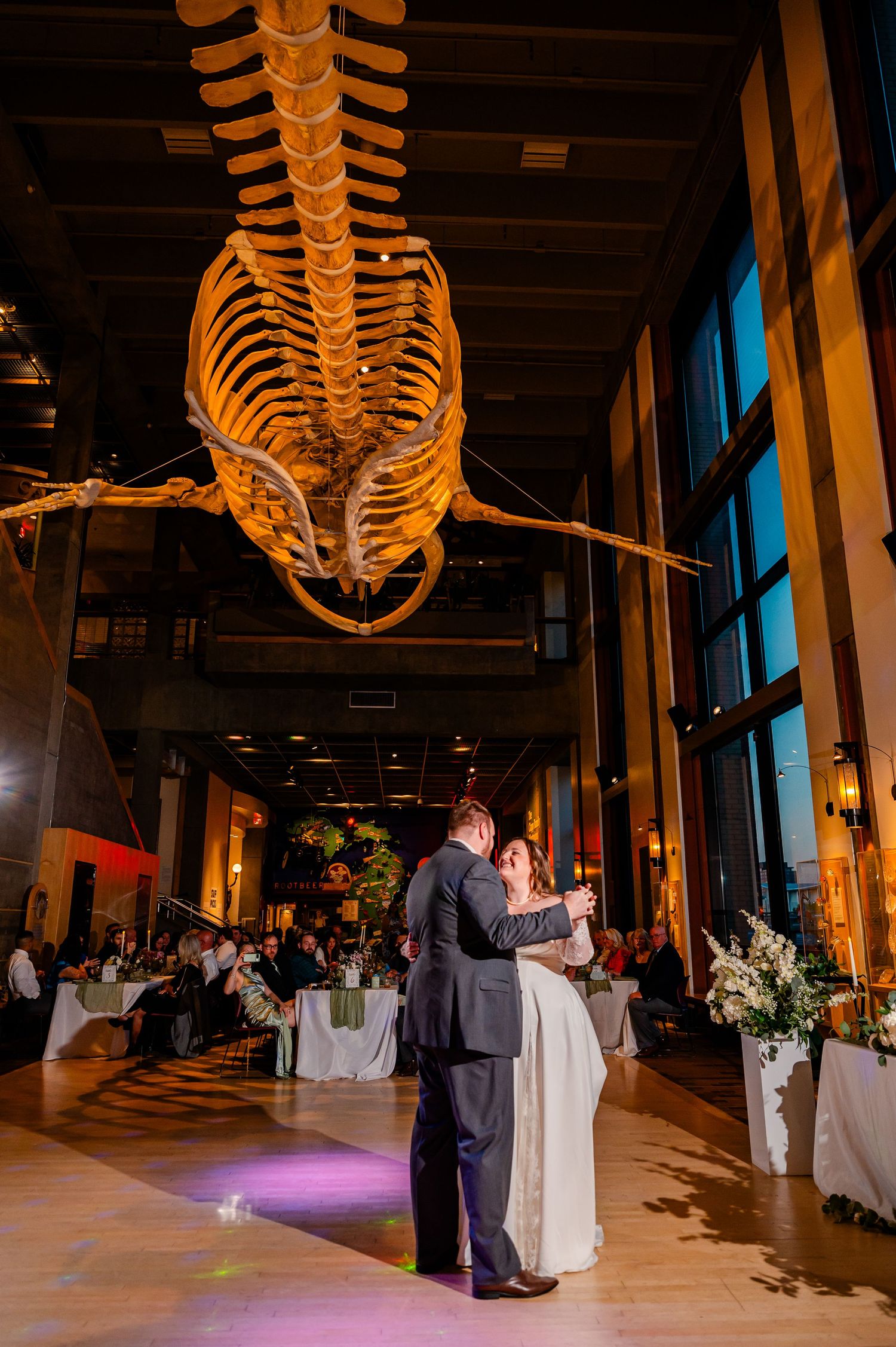 Couple shares first dance beneath a large whale skeleton at a unique museum wedding venue.