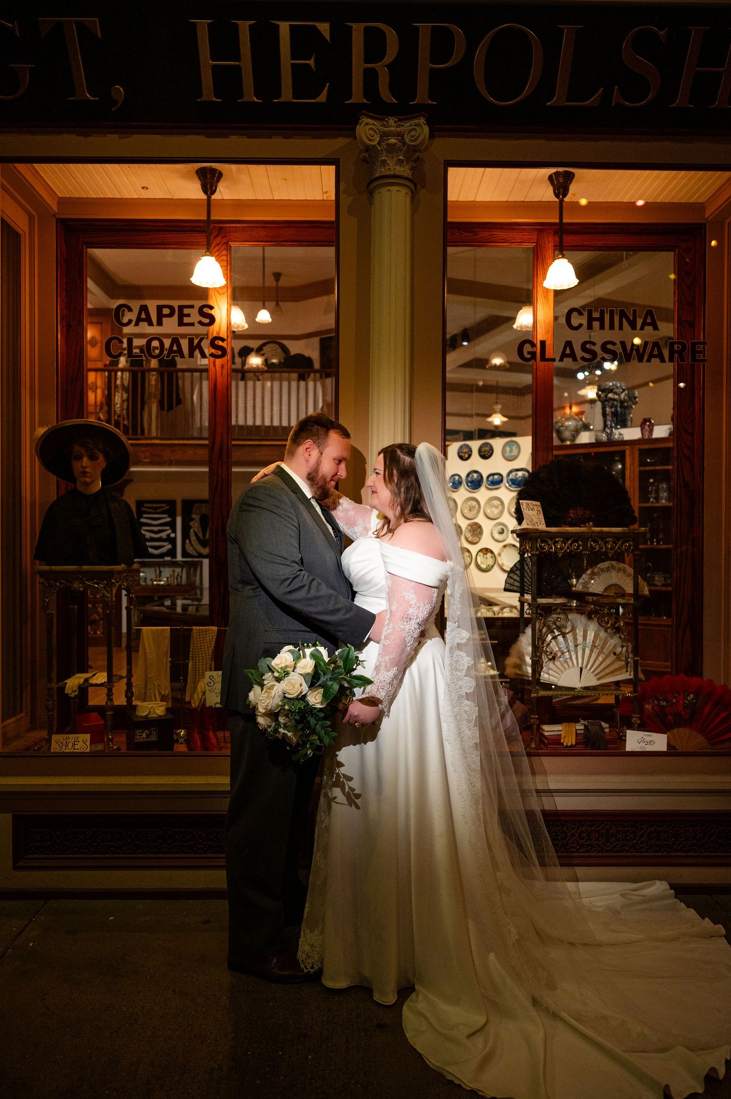 Bride and groom embrace in front of a historic Herpolsheimer storefront display on their wedding night.