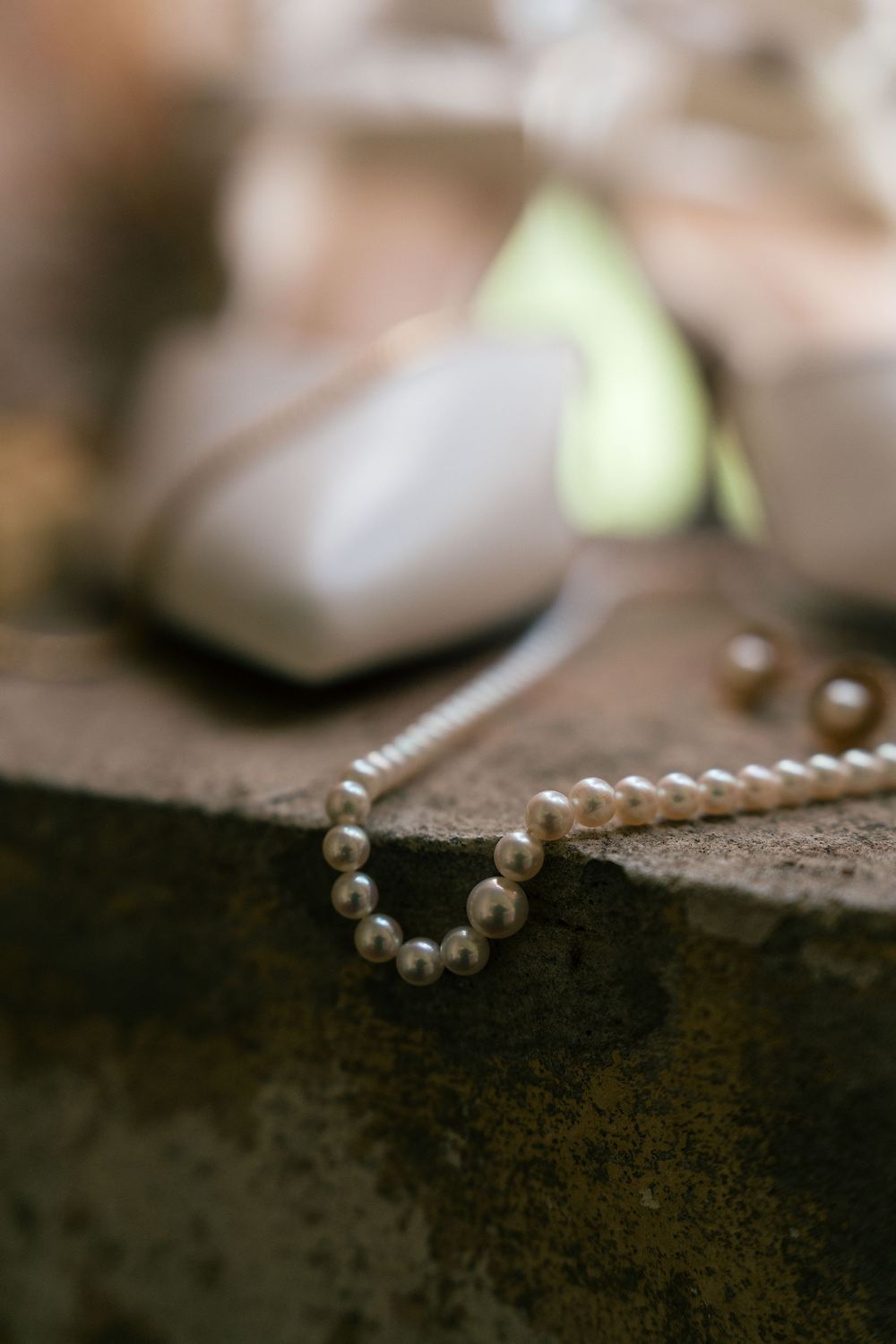 Close-up macro photograph of delicate white pearl necklace resting on dark textured surface with shallow depth of field.