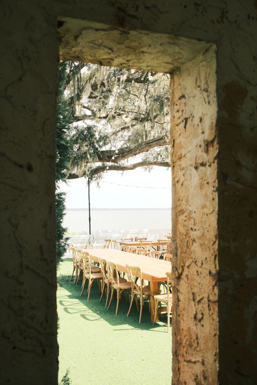 Stone archway overlooking outdoor seating area with wooden chairs.