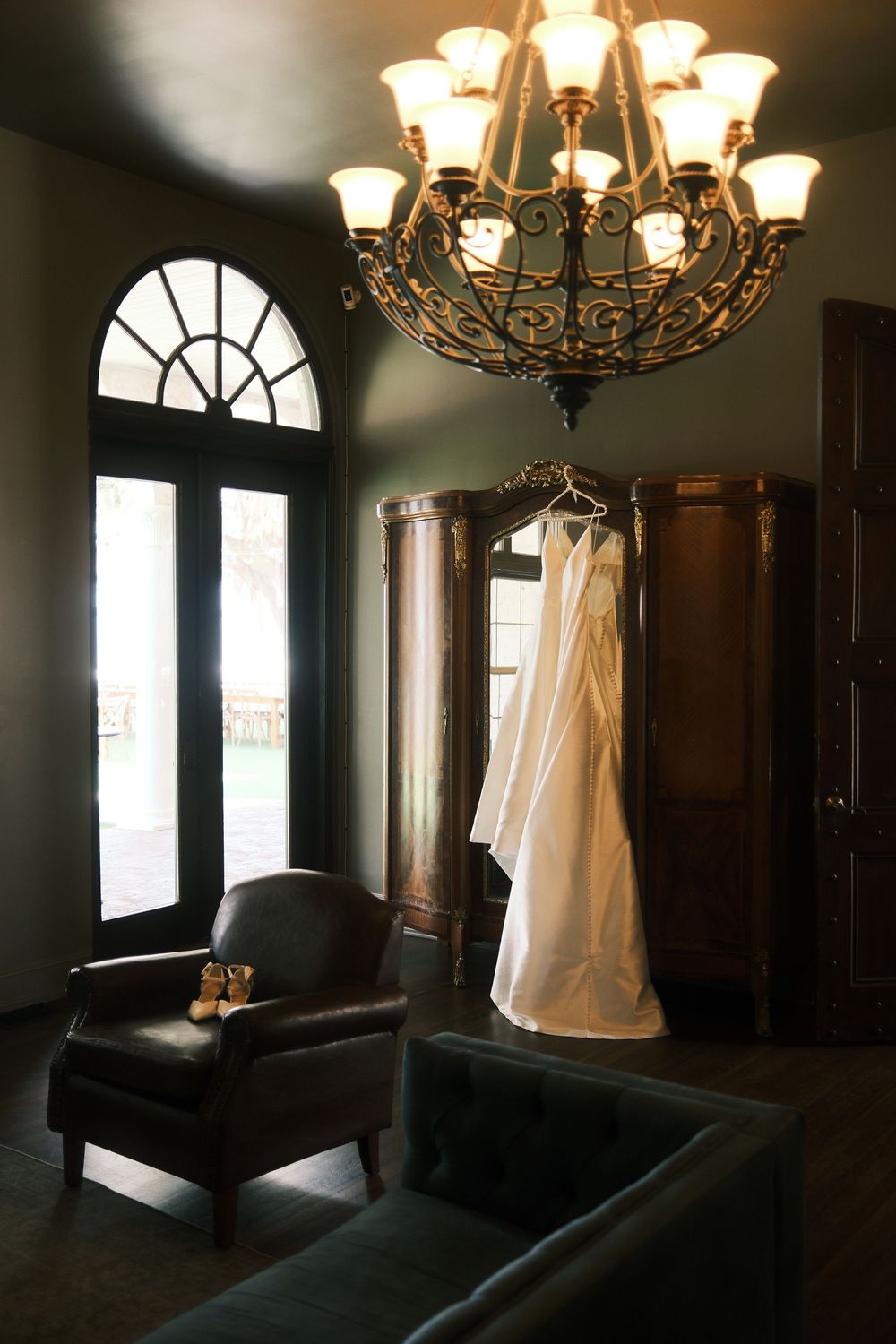 Elegant room with chandelier lighting and arched windows featuring dark furniture and white decor elements.