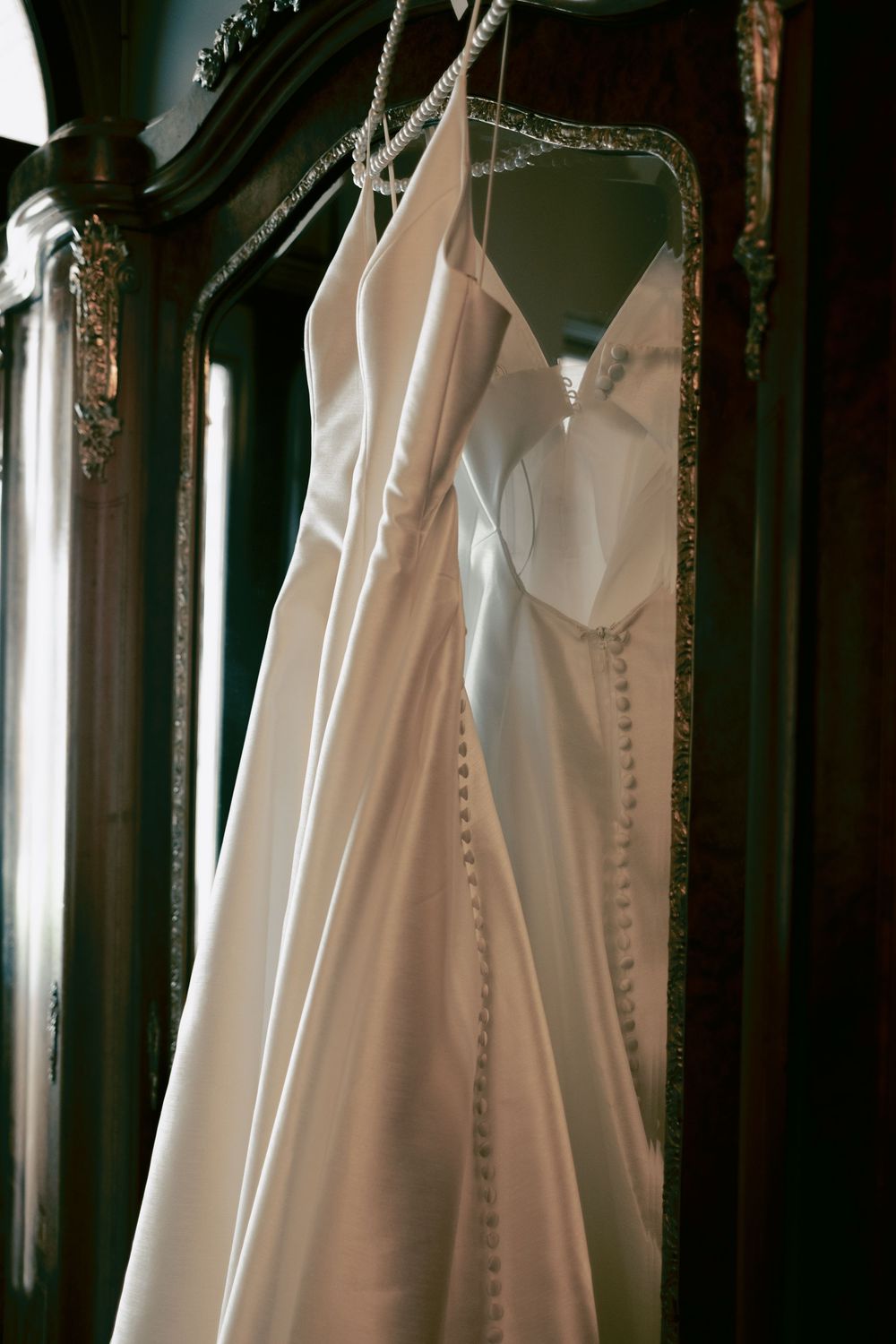 Elegant white wedding dresses hanging in a row against a dark background.