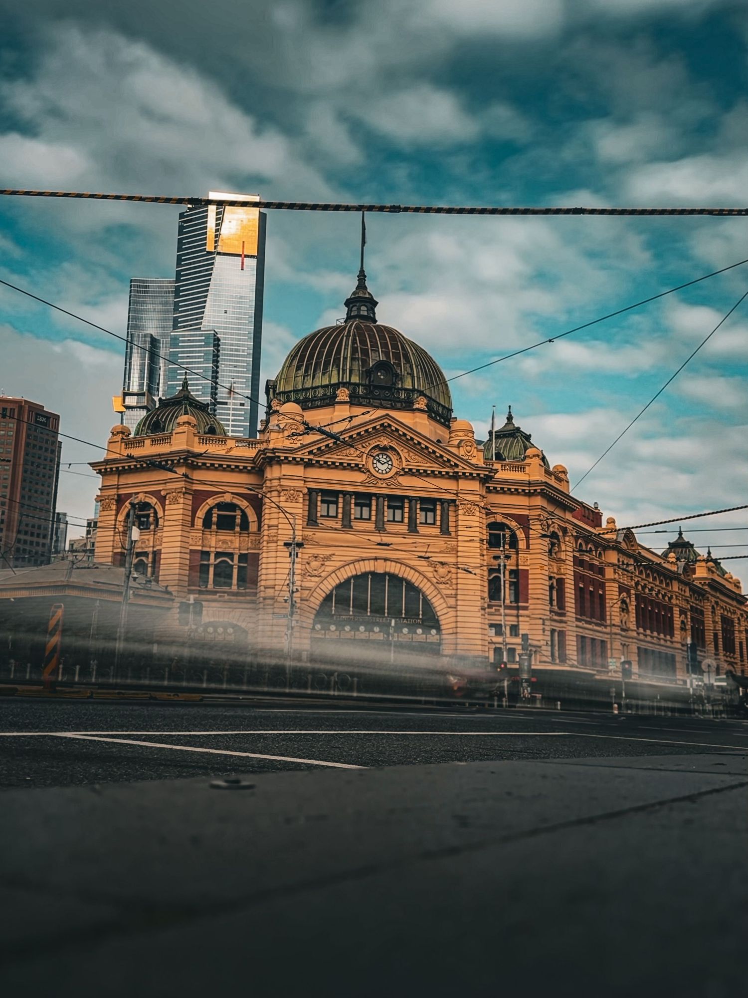 Historic Flinders Street Station with ornate dome architecture and passing tram in Melbourne.