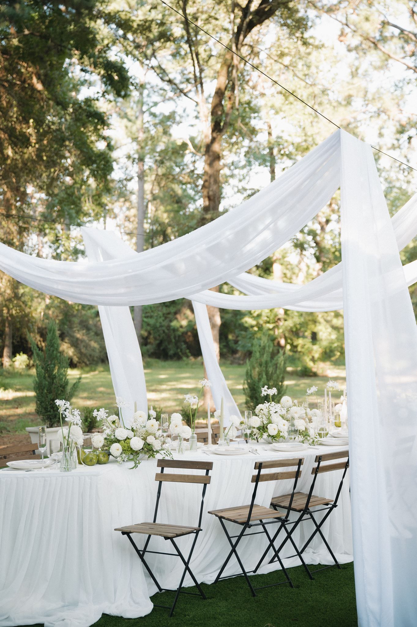 Elegant outdoor wedding reception with white draped canopy at Oak Atelier in Conroe, Texas.