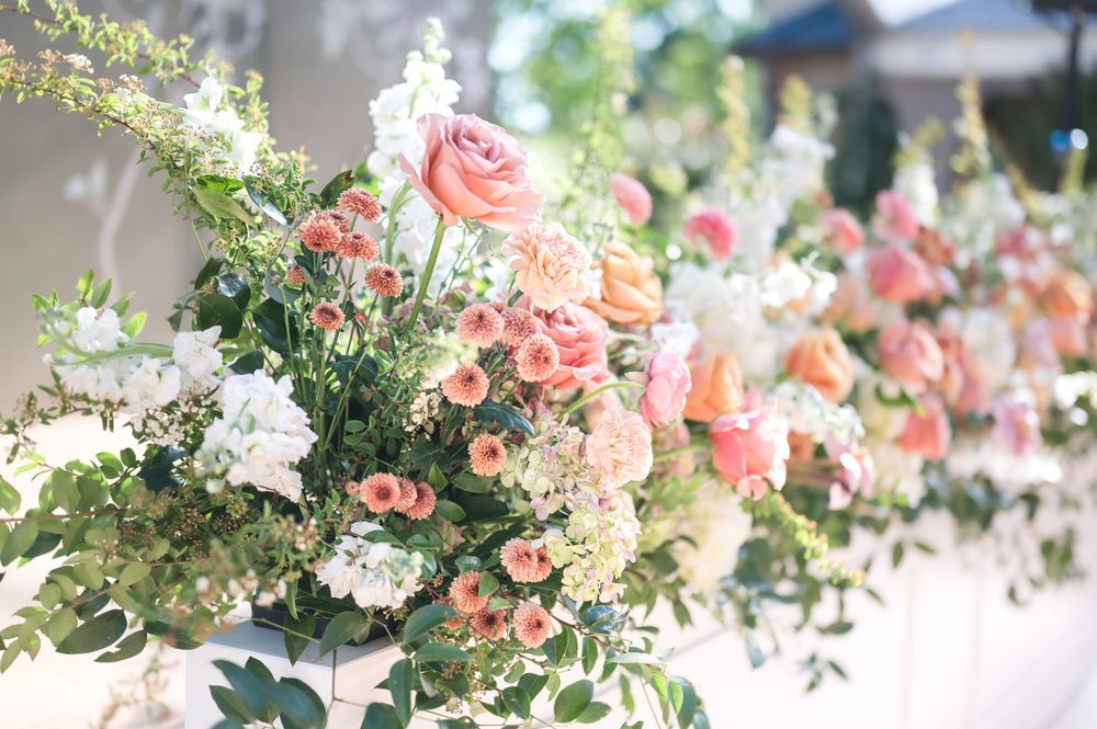 Elegant floral arrangement featuring soft pink roses and white blooms with greenery in natural sunlight.