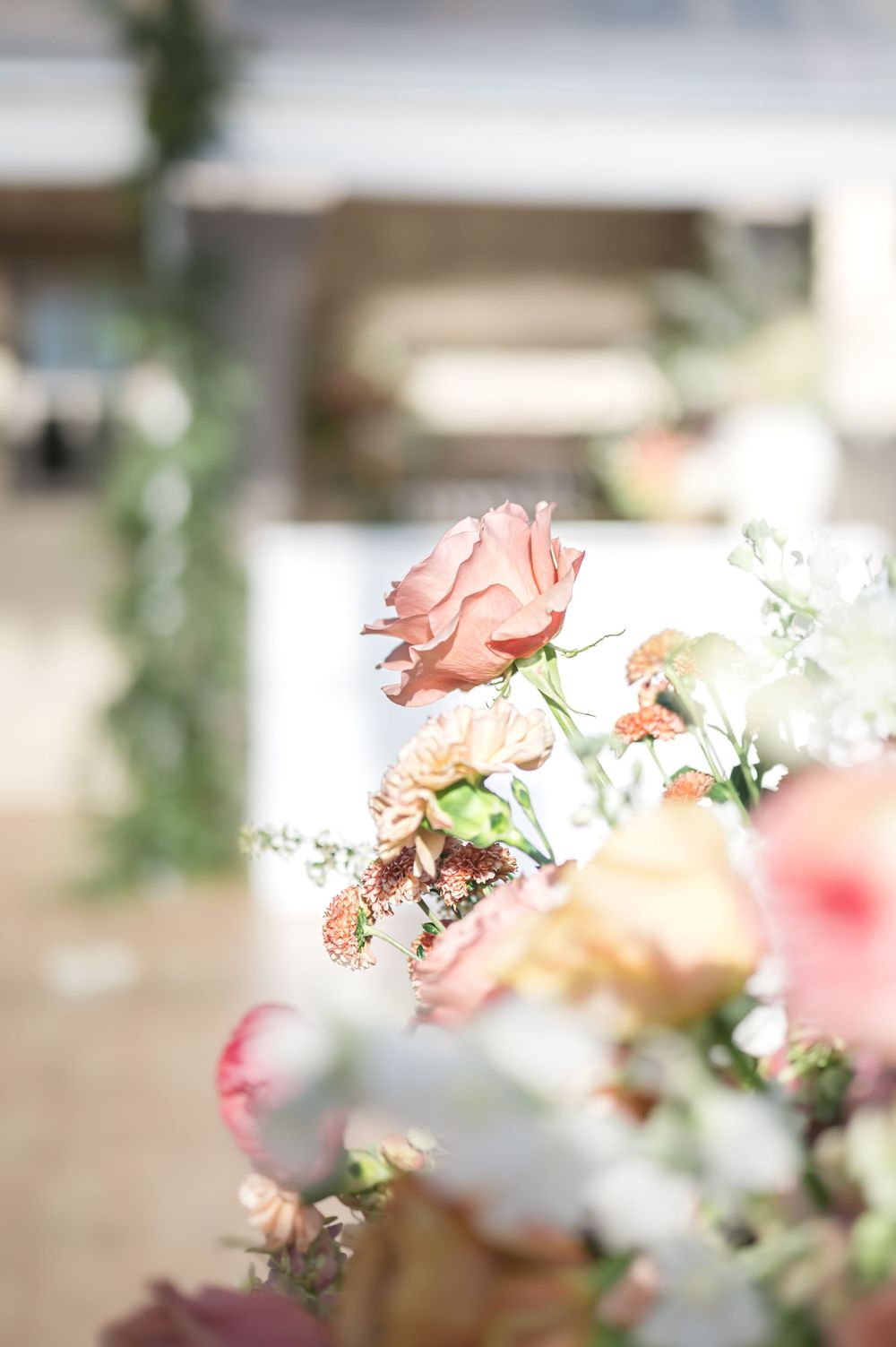 Soft focus close-up of delicate pink roses and white flowers in a romantic floral arrangement.