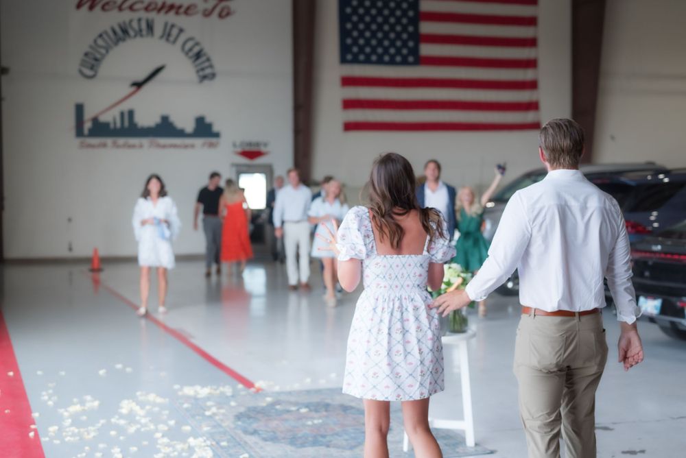 Guests gather at a celebration inside an aviation center decorated with an American flag.