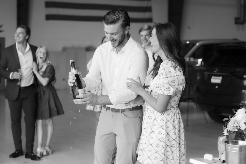 Black and white photo of couple celebrating with drinks at an aviation center.