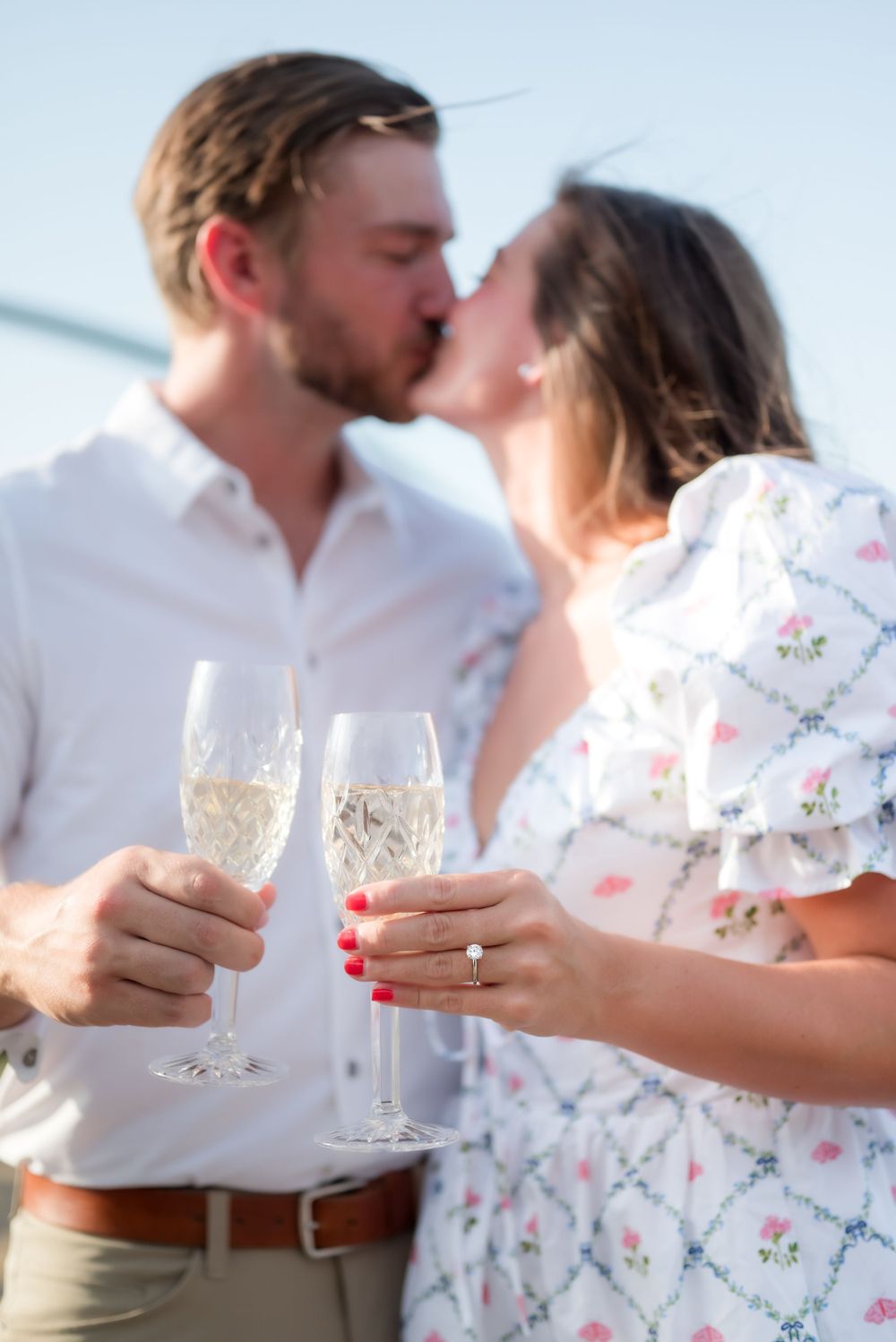 Two people toasting with champagne glasses while sharing a romantic kiss.