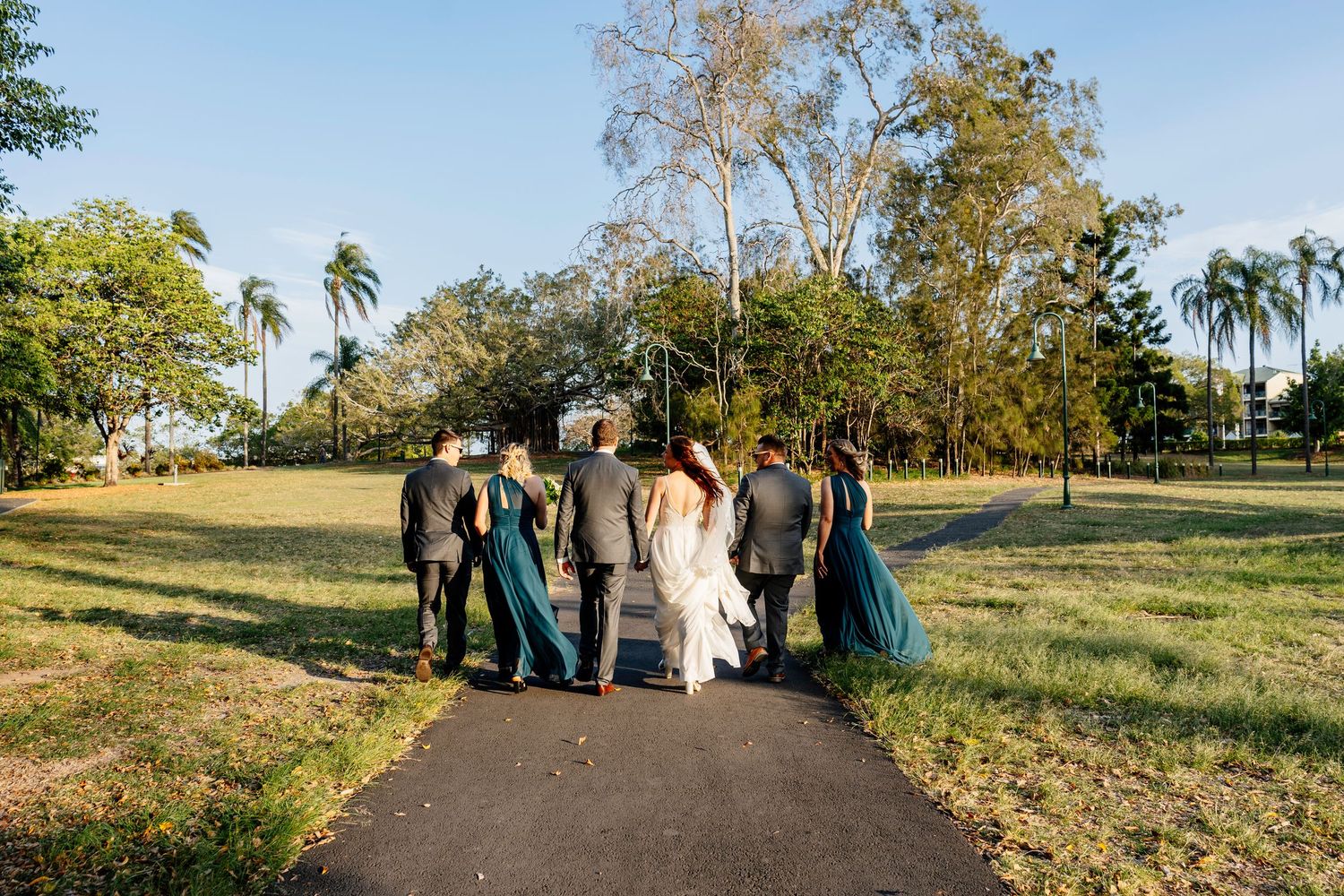 Wedding party posing under a large banyan tree, bride in white gown with groomsmen and bridesmaids in teal dresses Factory 51 Brisbane