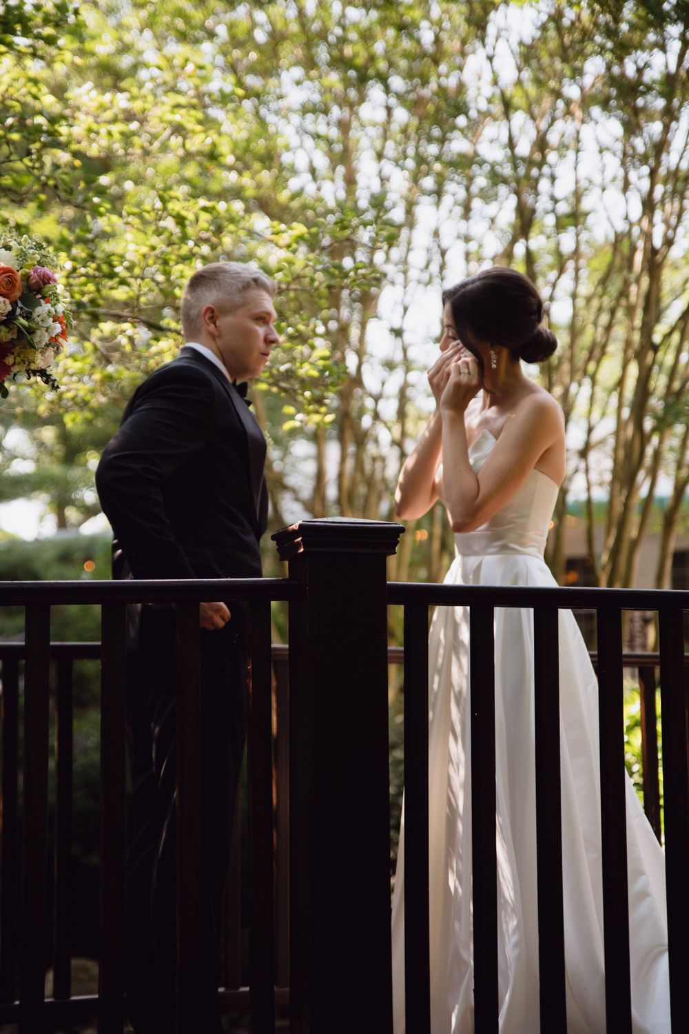 A tender moment shared on a wooden deck surrounded by lush greenery.