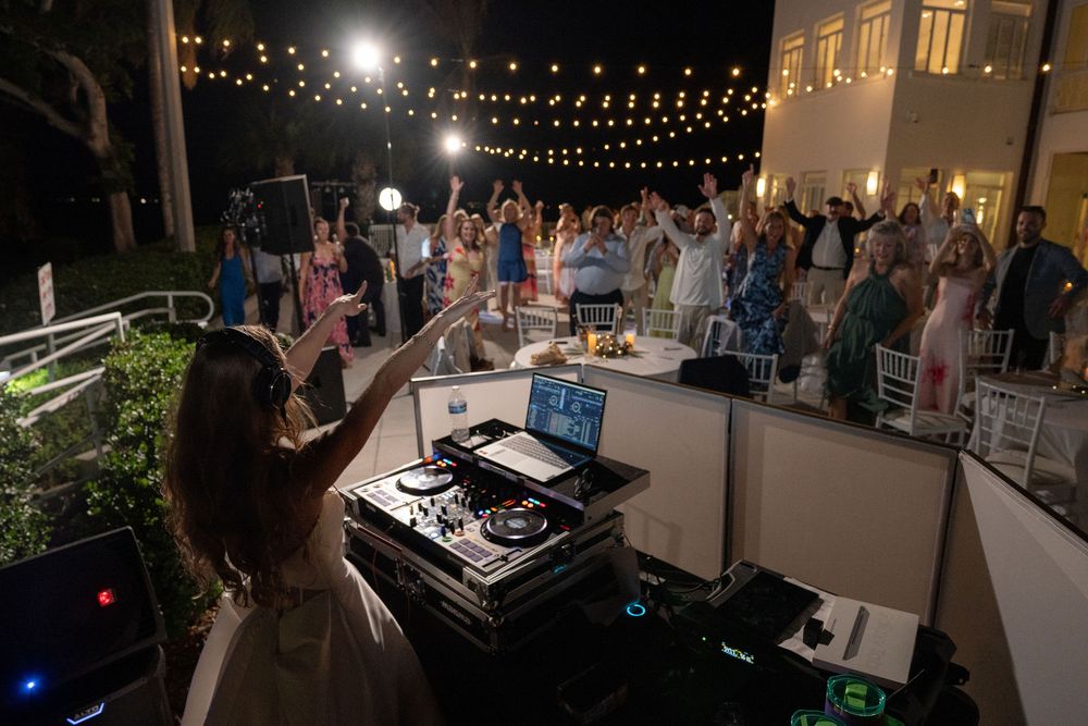 Bride with arms raised while DJing under string lights at The Mansion at Tuckahoe in Jensen Beach, FL