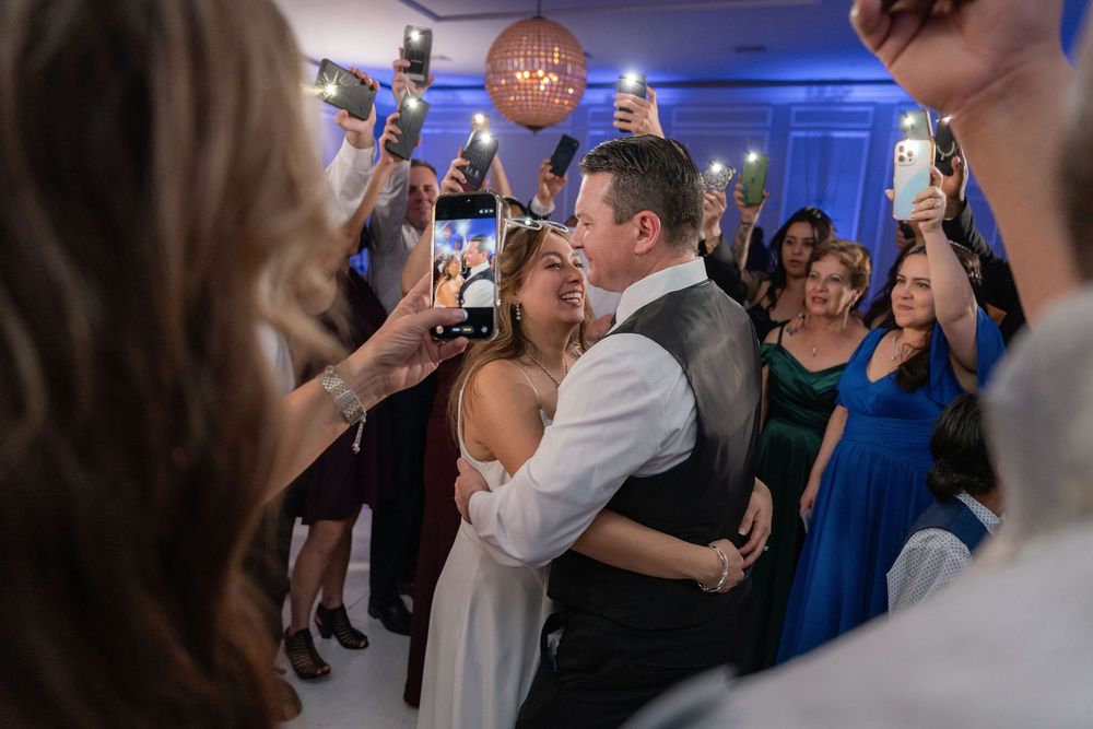 Newlyweds dancing while guests raise phone flashlights around them at The Wanderers Club in Wellington, FL
