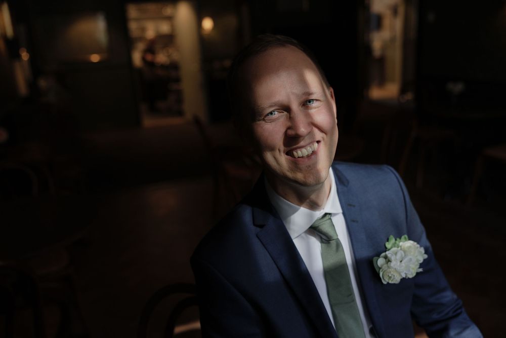 Smiling man in blue suit with green tie and white boutonniere corsage at wedding at Jonsered, Gothenburg