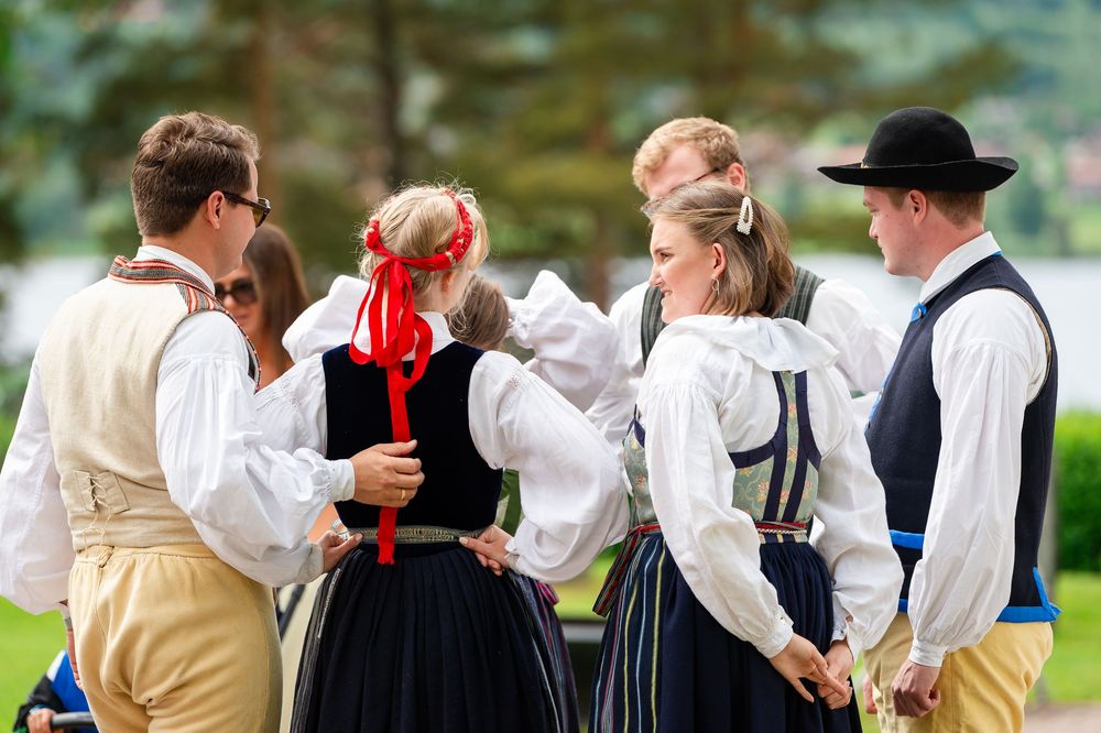 Group of people in traditional Scandinavian folk costumes dancing outdoors at a cultural festival.