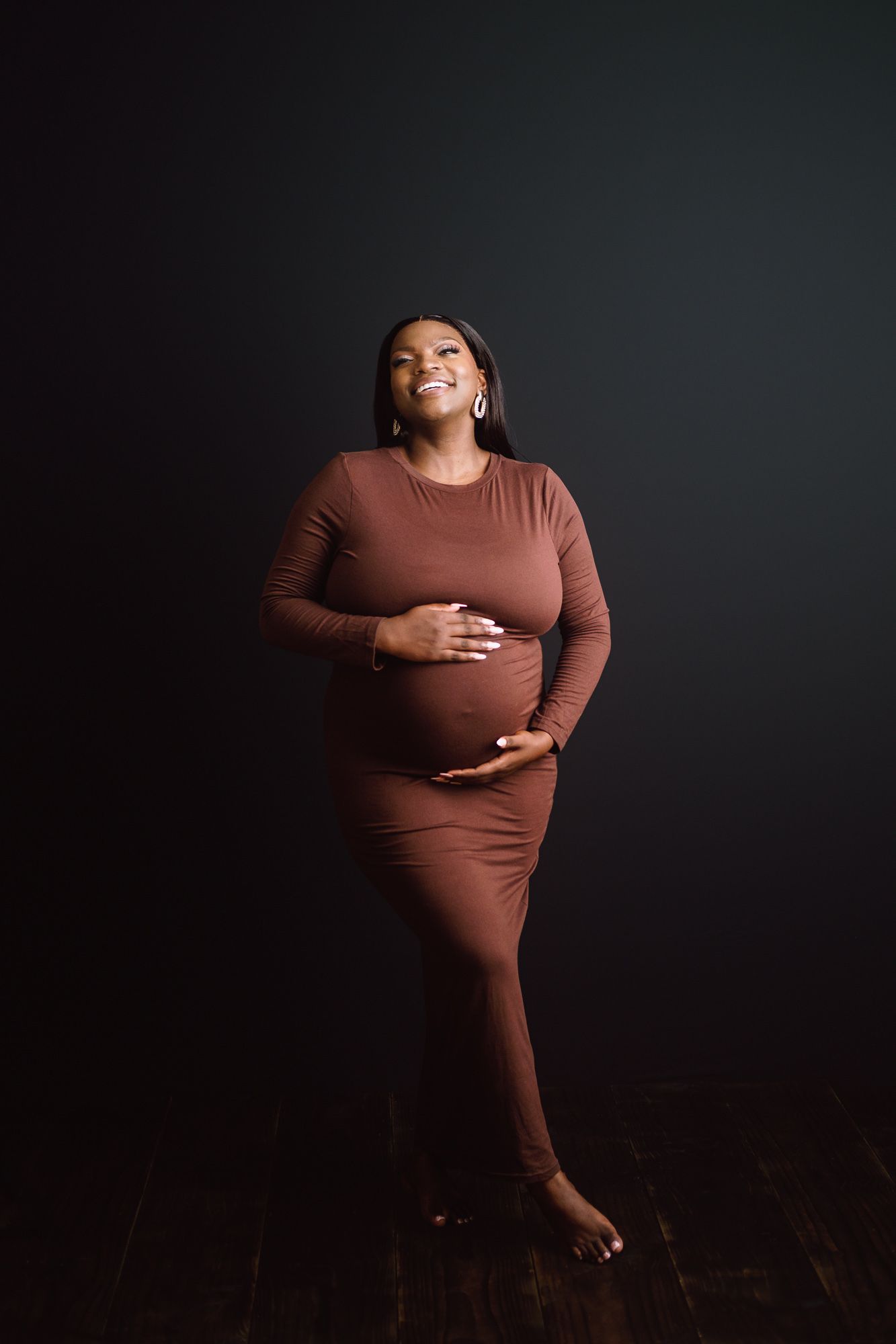 Elegant maternity portrait of woman celebrating pregnancy and motherhood against black background
