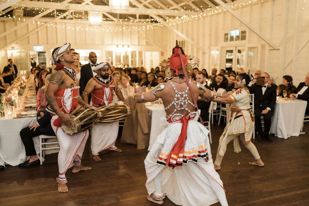 Traditional Sri Lankan Kandyan dancers perform at an elegant wedding reception with string lights and seated guests.