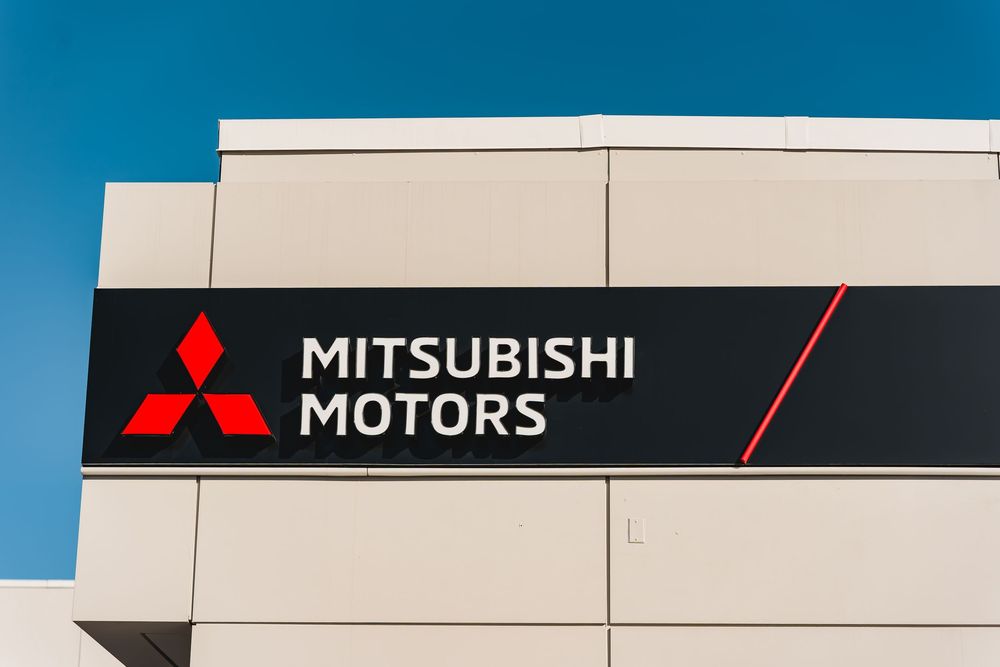 Mitsubishi Motors dealership sign on a modern building facade against a clear blue sky.