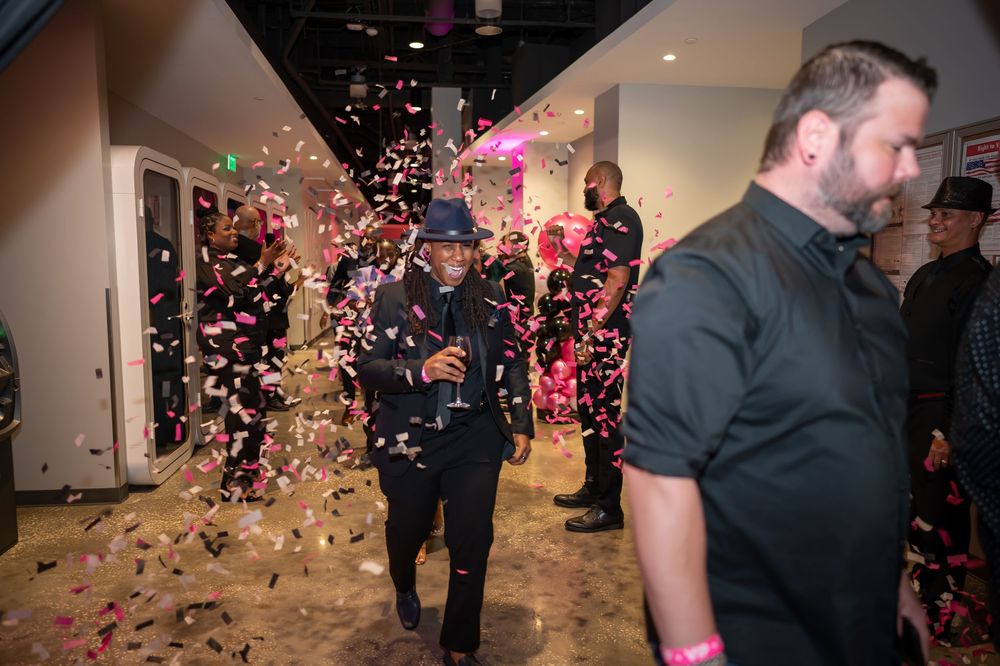 People celebrating at a party with colorful confetti falling in a festive venue.
