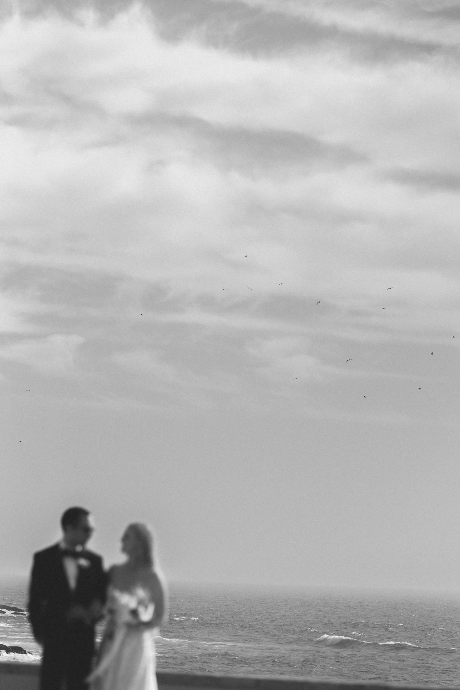 Artistic black and white portrait of the bride and groom overlooking the Atlantic Ocean during their destination wedding in Cascais, Portuga