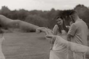 Black and white wedding photo of bride and groom sharing a tender moment outdoors on a lush green lawn.