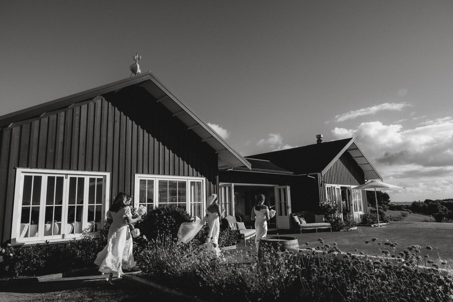 White directional sign for Mudbrick Vineyard pointing to restaurants, The Lodge, Merlot Cottage, and Olive Cottage.
