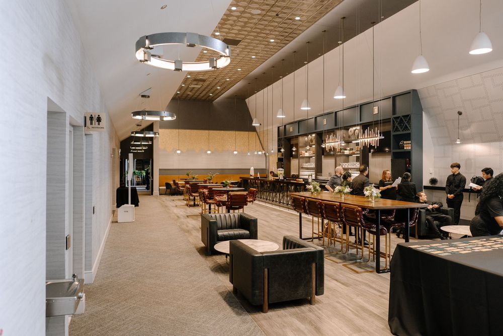 Modern restaurant lounge with leather seating, pendant lights, and an elegant bar area with high stools.