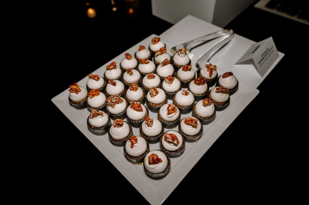 Elegant tray of mini dessert cups topped with cream and candied nuts at a catered event.